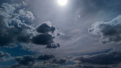 Dramatic sky with dark clouds and a bright sun illuminating the scene, creating a striking contrast. Perfect for backgrounds, weather themes, or artistic projects.