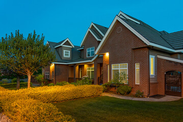 Two story stucco luxury house with nice Spring blossom landscape at night in Vancouver, Canada,...
