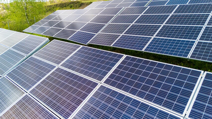 Aerial view of solar panels arranged in rows, capturing sunlight in a green environment. This image showcases renewable energy production and sustainable technology.