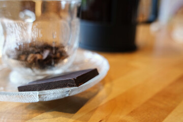 Piece of chocolate with a cup of coffee behind on a table
