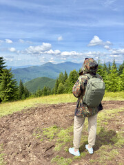 Reaching the summit.Woman hiker with backpack admiring the stunning panoramic mountain view from a summit. Concept of adventure, summer travel.Freedom and exploration.Active lifestyle and recreation