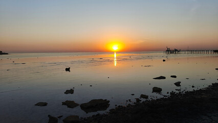 Bright orange sun setting or rising over the horizon with the sea in the background. Sunrise or...