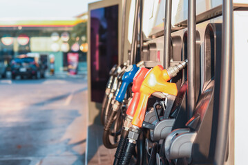 Colorful fuel pump nozzles arranged in a row at a modern gas station during daylight, symbolizing...