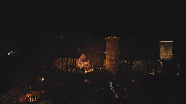 Aerial night view Lamproba festival with villagers gathered around symbolic bonfires near church and medieval tower in Svaneti.Concept welcoming arrival of spring, invite the blessings of the gods