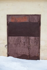 Rusty metal door with visible corrosion stands in urban setting