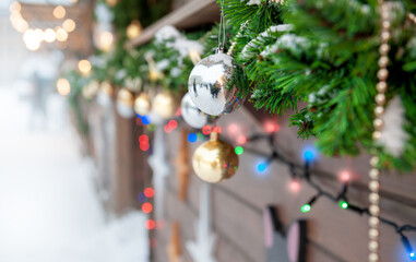 Christmas ornaments and pine garland hang with glowing festive lights. Perfect for holiday, seasonal street decor themes