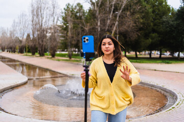 Influencer creating content in urban park using smartphone and tripod