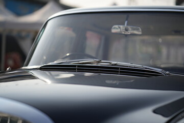 The windshield and chrome wipers of a classic car showcase the timeless allure of vintage...