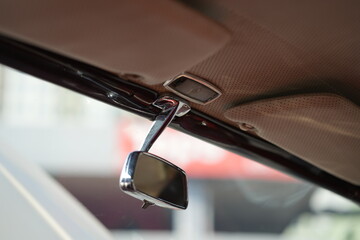 The rearview mirror of a classic car has a shiny chrome finish with a simple design, serving as a...