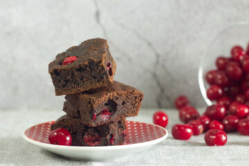 a vertical shot of a chocolate cake with cherries and chocolate on the table