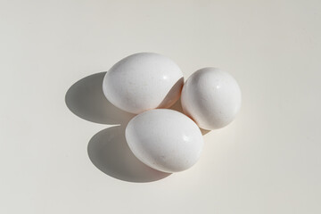 Three Fresh White Eggs on a Clean, Bright Surface with Shadows