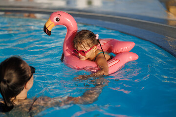 mom and daughter in pool have fun during summer vacation. Child having fun in swimming pool. 