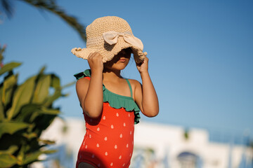 Funny little girl relaxing on summer vacation. The child has fun on the beach. Cute baby in a colorful swimsuit and sunglasses is resting.