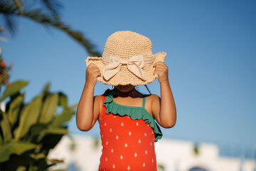Funny little girl relaxing on summer vacation. The child has fun on the beach. Cute baby in a colorful swimsuit and sunglasses is resting.