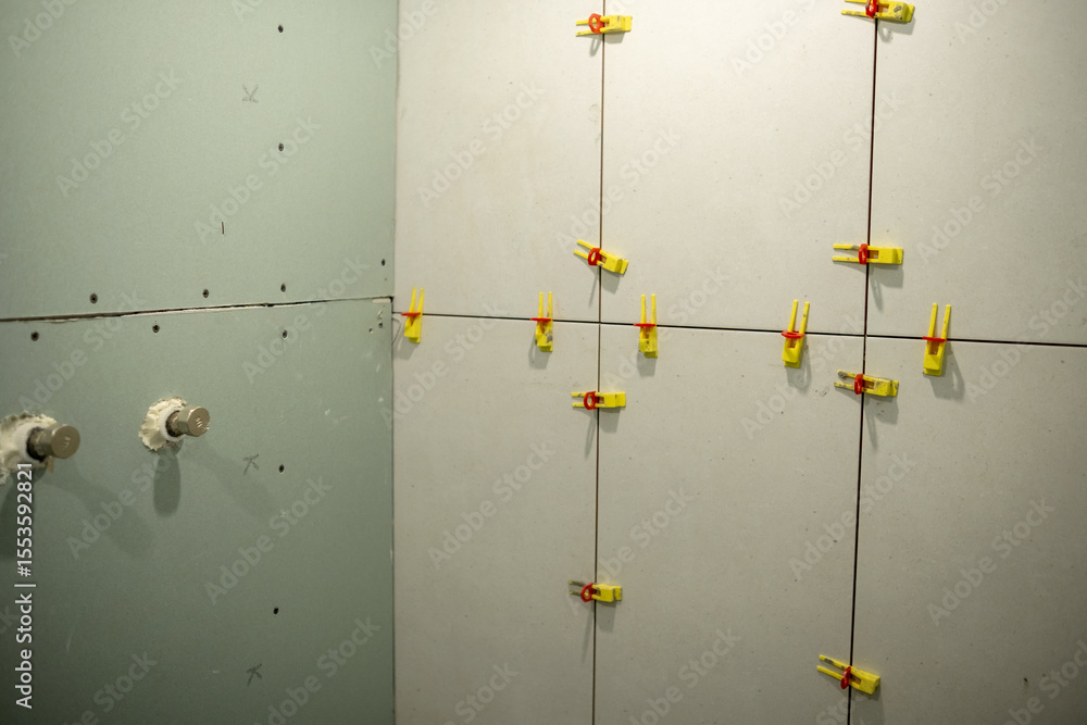 Poster drywall installation in progress with clamps securing panels in a construction project
