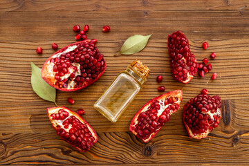 Glass bottle of pomegranate seed oil in a glass bottle and fresh fruit on a table, top view