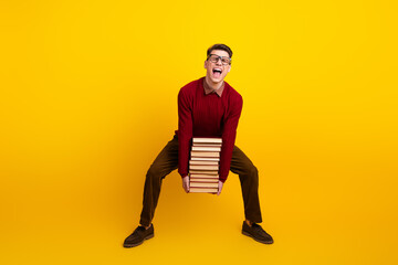 Handsome Intelligent student Young Happy Male Holding Stack of book Over Vibrant Yellow Background