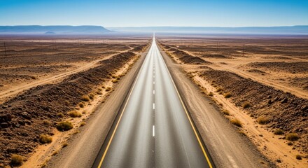 Fototapeta premium Endless desert highway under clear blue sky in barren landscape