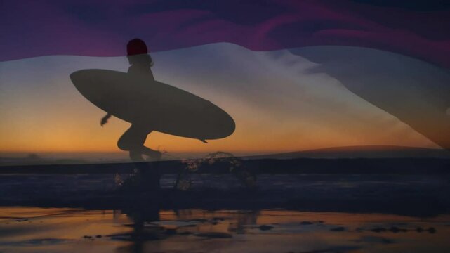 Surfing showing surfer walking into sunset surf and adjusting board grip as wave lifting board