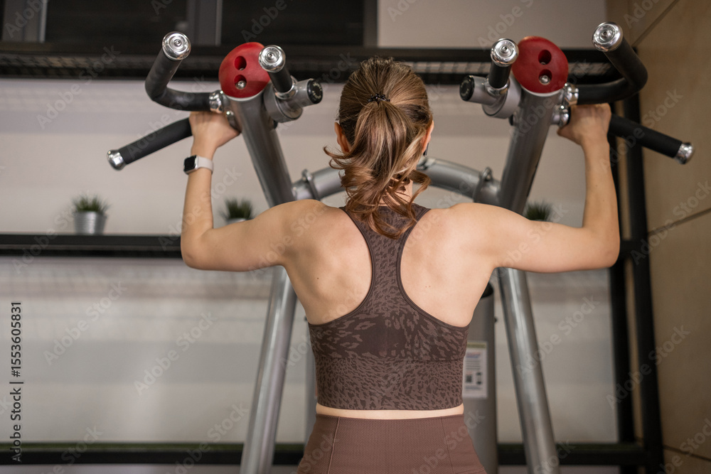 Poster fitness enthusiast performing a strength training exercise in a modern gym environment during daytim