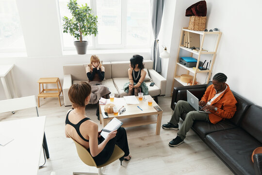 young adult woman working with colleagues and friends in modern workplace socializing and collaborating in business environment Gen Z - Powered by Adobe