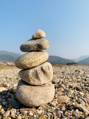 Stacked smooth river stones balanced carefully against a clear blue sky