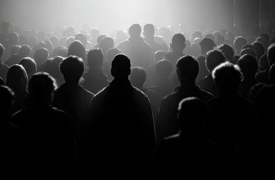 A large crowd viewed from behind, bathed in light from above