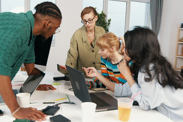 Young adult woman coworker presenting ideas to colleagues in a modern workplace, showing...
