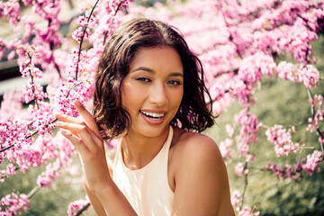 Cute beautiful young woman enjoying a sunny day in a blooming botanical garden during spring