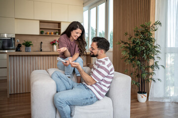Young couple relaxing on sofa, browsing catalogs and discussing home improvement