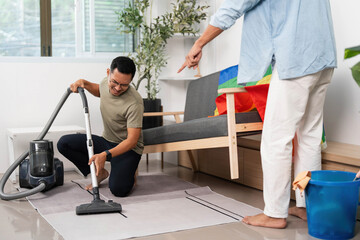 Cleaning Together. Friends engaging in household chores with a rainbow flag in their living space.