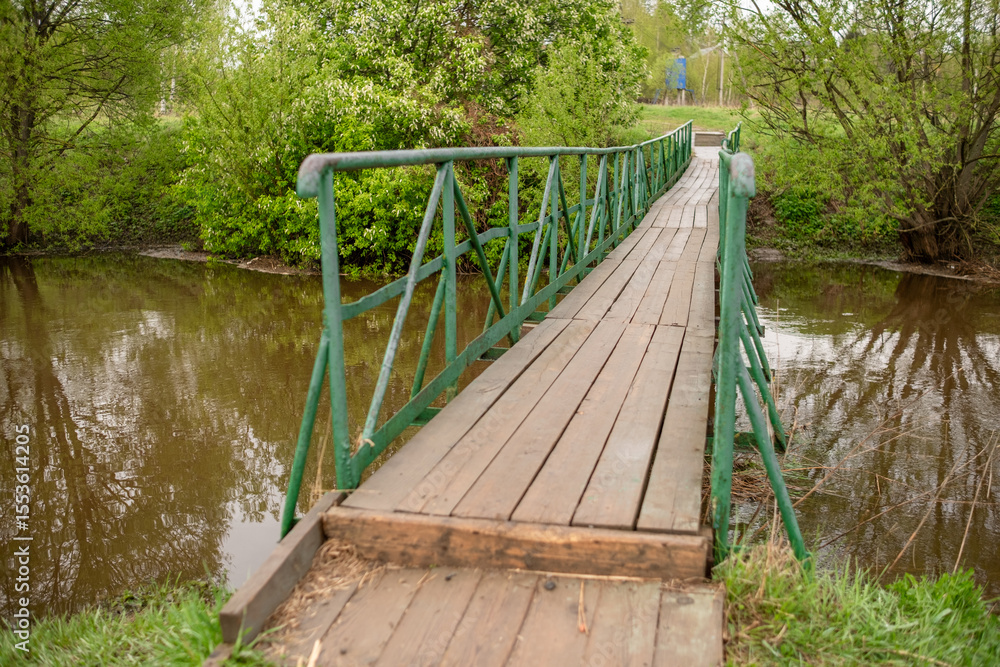 Aufkleber wooden bridge over a peaceful stream surrounded by greenery in a serene countryside setting during s