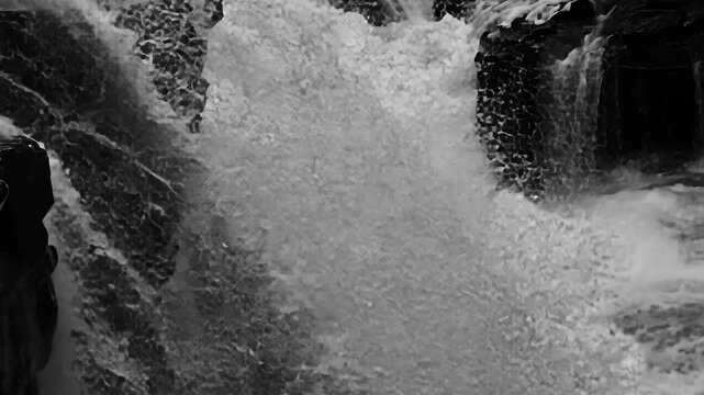 Upper falls of Aysgarth in full flow during midday sunlight showcasing natural beauty in striking black and white, Mid side on shot of the upper falls at Aysgarth falls on the river ure
