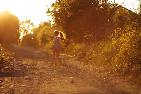 Happy girl runs along a country road.