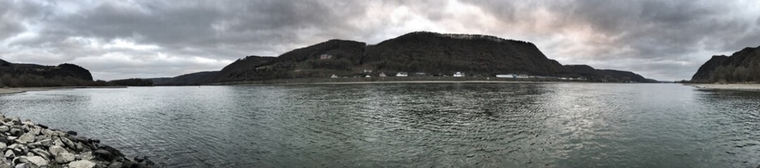 Panoramic view showcasing a tranquil riverside surrounded by rolling hills