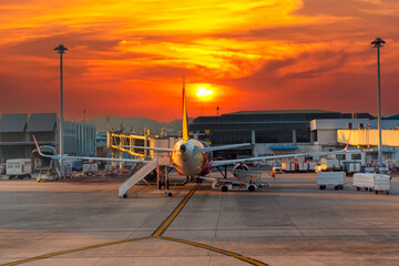 A passenger airliner parked at an airport terminal during a picturesque sunrise