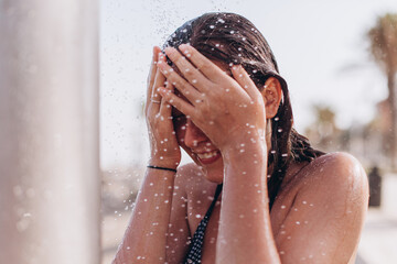 Tourist enjoying refreshing shower on beach during summer vacation