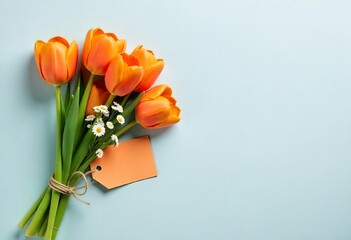 A bouquet of orange tulips and small white flowers placed on a light gray background, with two orange tags attached to the stems, with blank space text