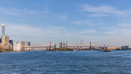 Naklejka premium Queensboro Bridge spanning the East River in New York City with Roosevelt Island in the middle on a blue sky day. 