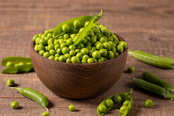 Fresh green peas and pods in a bowl on wooden table. Vegetable healthy food.  