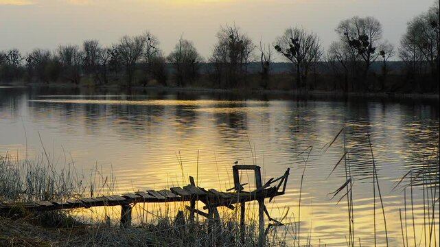 View of Seversky Donets river in the countryside. Landscape of river with a small old wooden pier - a place for fishing. Sunlight reflects off the waves on the water