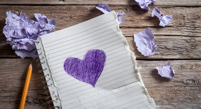 Notebook page with a torn purple heart sketch on wooden table for Valentine's Day with copy space