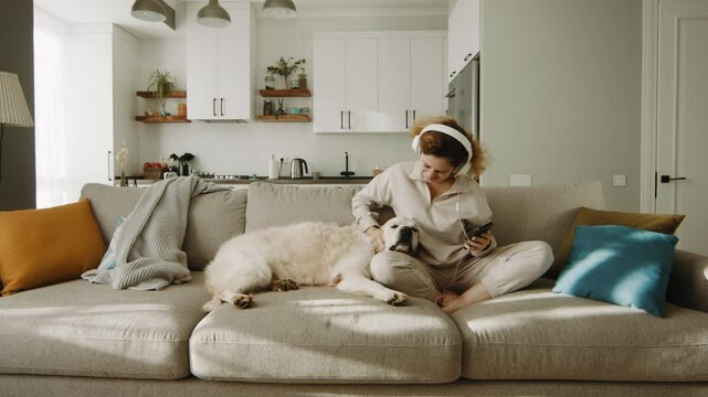 Golden retriever lays head on womans lap as she dances and kisses dog with joy