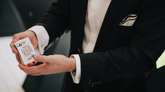 A magician performs magic tricks with a deck of cards. Shooting the magician's hands