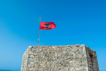 Albanian flag flies over Ali Pasha Tepelena Fortress Porto Palermo. Albania.
