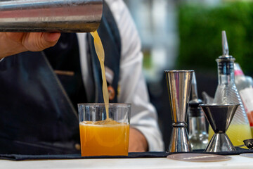 Bartender mixing orange cocktail with ice on a night club