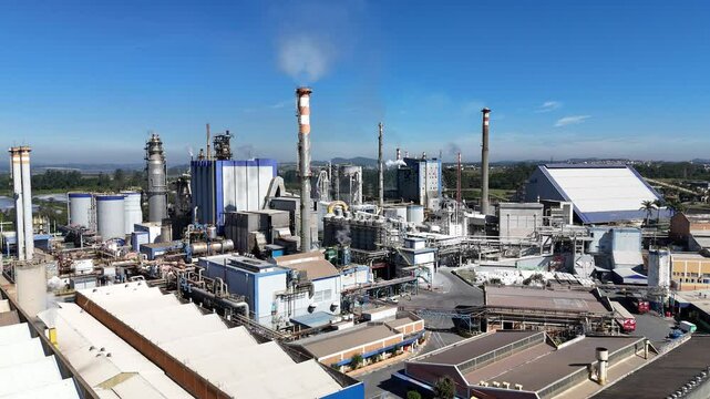 Vis&atilde;o a&eacute;rea de chamin&eacute;s e equipamentos soltando vapores e poluentes em uma ind&uacute;stria de papel e celulose