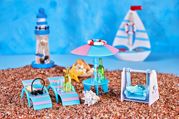 image of a summer relaxation corner on a sea beach with chaise longues, a stand with an umbrella and a swing on a blue background with a sailboat and a lighthouse