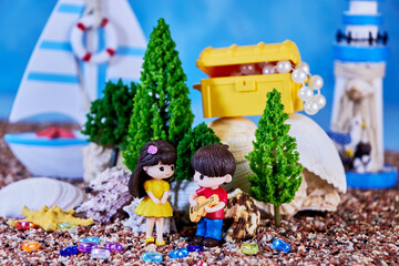 summer romantic doll composition with a girl and a boy who plays her a song on a guitar about the treasure of his love on the seashore