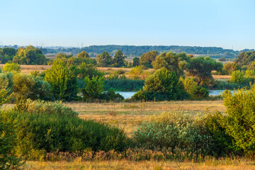 Scenic valley of the river in eastern region of Ukraine. Countryside nature with yellow meadows and green bushes and trees in late summer and early autumn